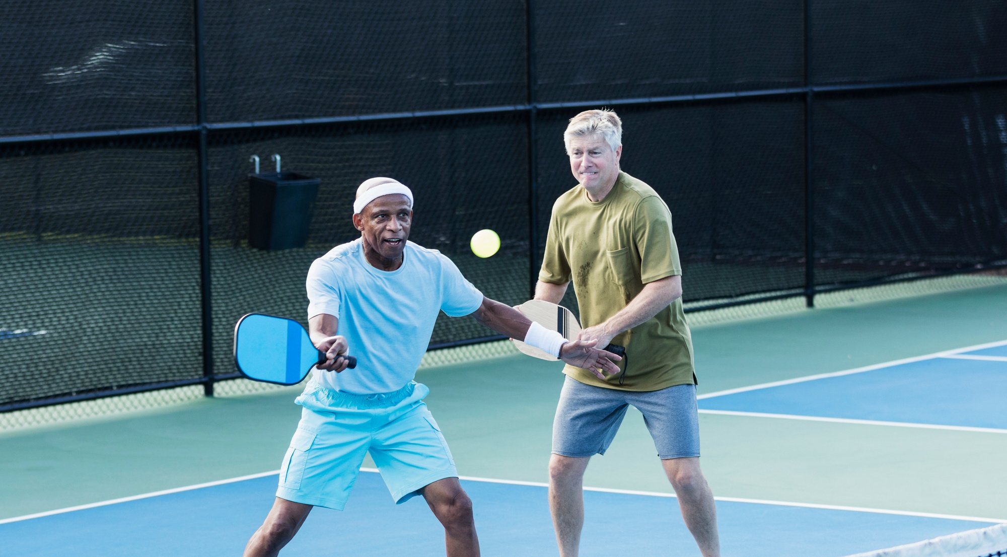 Senior men playing pickleball, hitting ball